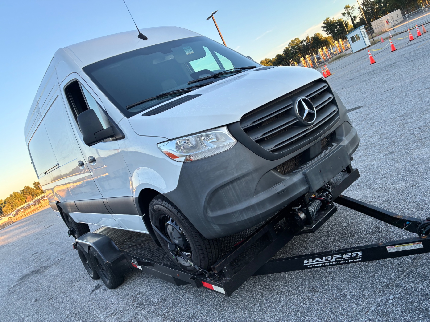Front of a Sprinter van winched onto a flatbed trailer with wheel tie-down straps