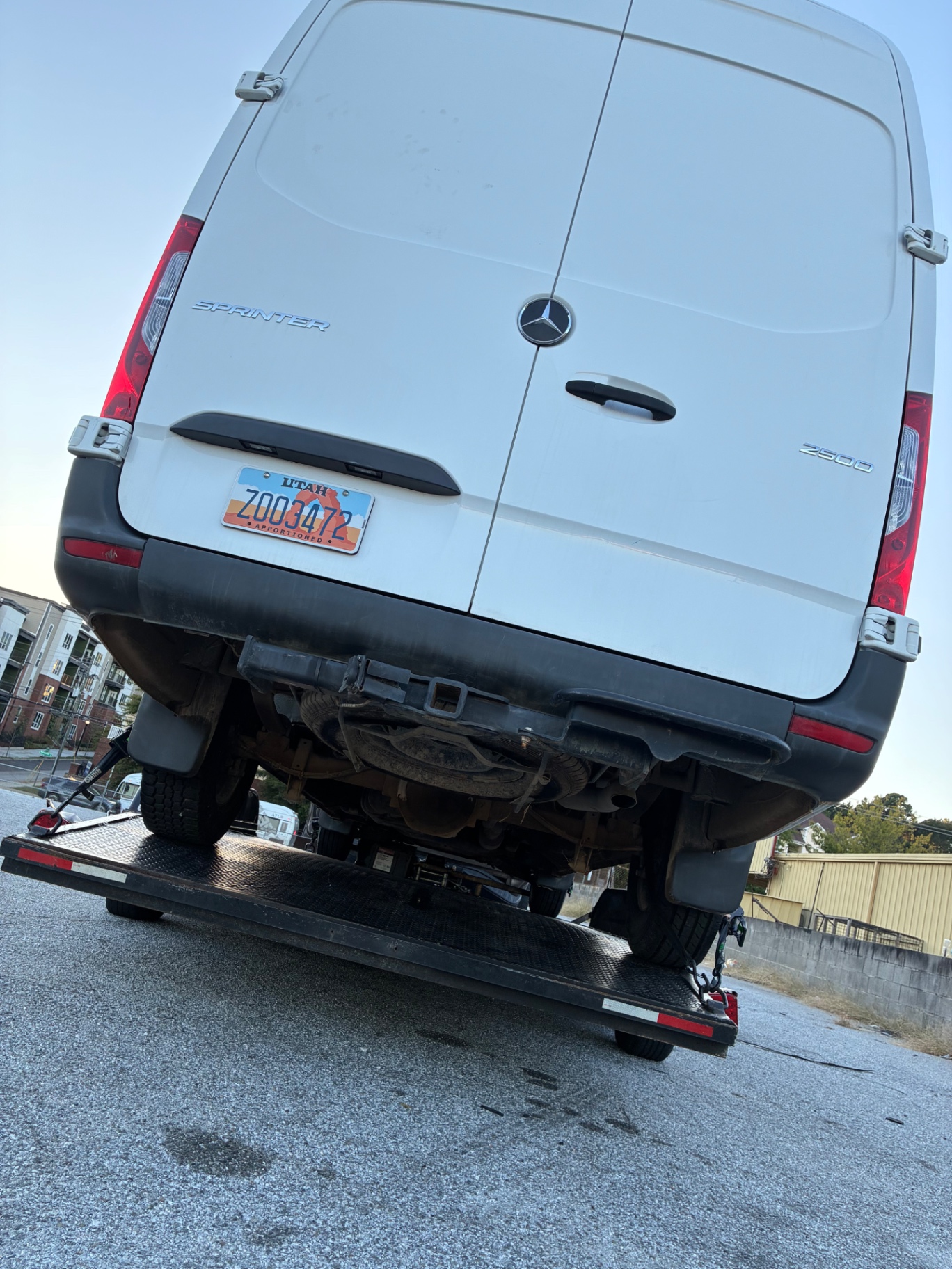 Rear of a Sprinter van strapped to the tail of a flatbed tow trailer